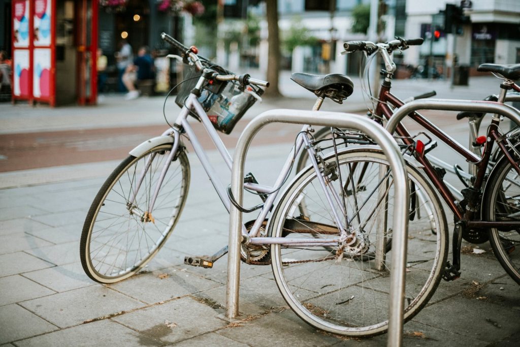 Cyklar fastlåsta vid bågformade cykelställ i stål på en gata